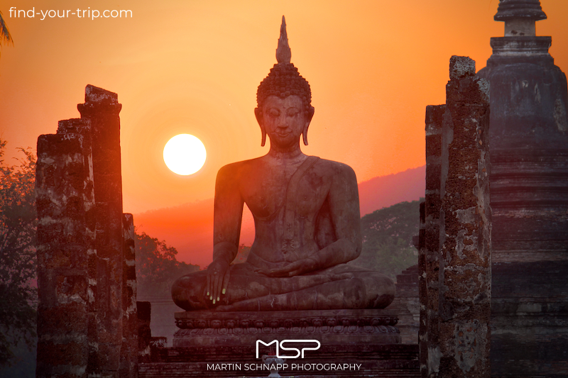 Sunset behind the Buddha statue of the <b>Mahathat Temple</b> in the Historical Park of <b>Sukhothai</b> in <b>Thailand</b> <a href='https://find-your-trip.com/?t=guide&poi=th40204&lang=en' target='fyt'><nobr>[ ⭢	map ]</nobr></a>