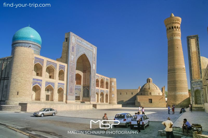 The Kalan minaret (early 12th century) is the oldest building on <b>Poi Kalan</b> in <b>Bukhara</b> in <b>Uzbekistan</b>. It is said to have been built under the Qarakhanid ruler Arslan Khan. On the right edge of the picture is the Kalan Mosque (completed in 1514), on the left opposite is the Mir Arab Madrasa (completed in 1536/37) and on the south side of the square is the Alim Khan Madrasa (early 20th century). <a href='https://find-your-trip.com/?t=guide&poi=uz7651&lang=en' target='fyt'><nobr>[ ⭢	map ]</nobr></a>